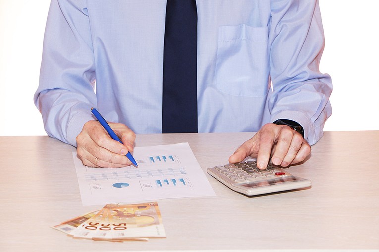 Businessman Looking at Figures with Euros on Desk
