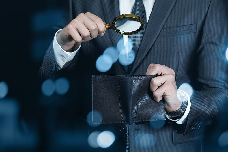 Businessman Looking in Wallet with Magnifying Glass