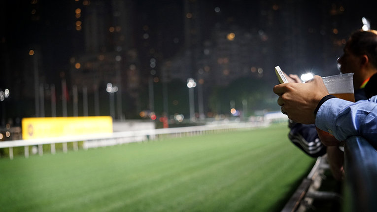 Man Betting on Phone at Horse Race