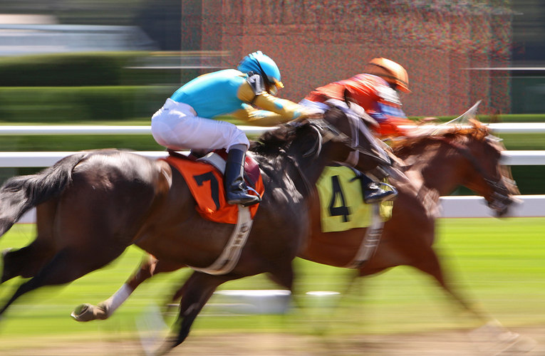 Two Blurred Horses Racing on Dirt