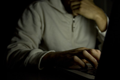 Man Typing on Laptop in Dark Room